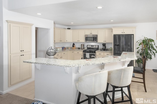 756 Megan Way, Fallon, NV 89406 - kitchen with appliances with stainless steel finishes, cream cabinetry, light tile patterned floors, a kitchen bar, and recessed lighting