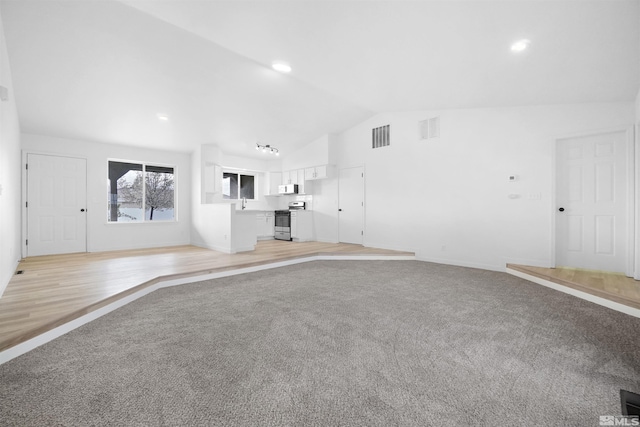 604 Venturacci Ln, Fallon, NV 89406 - unfurnished living room featuring vaulted ceiling, light carpet, recessed lighting, and a sink