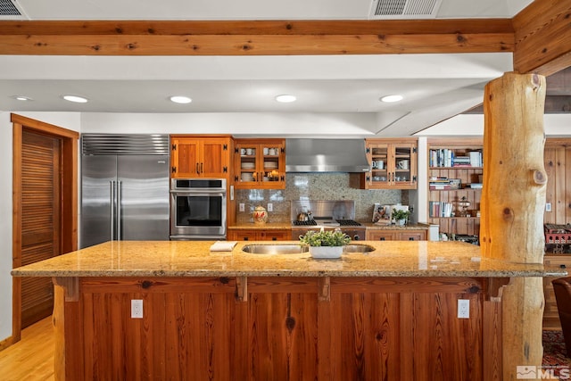929 Northwood Unit 68, Incline Village, NV 89451 - kitchen with appliances with stainless steel finishes, wall chimney range hood, brown cabinets, a kitchen breakfast bar, and recessed lighting