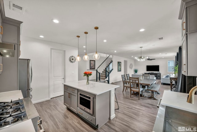 2181 Wyaconda Dr, Sparks, NV 89436 - kitchen featuring gray cabinets, appliances with stainless steel finishes, open floor plan, light wood-type flooring, and a kitchen bar