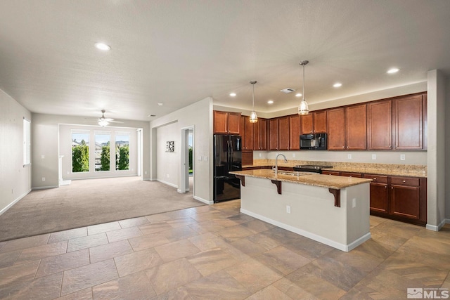 kitchen with black appliances, baseboards, a breakfast bar area, light stone countertops, and open floor plan