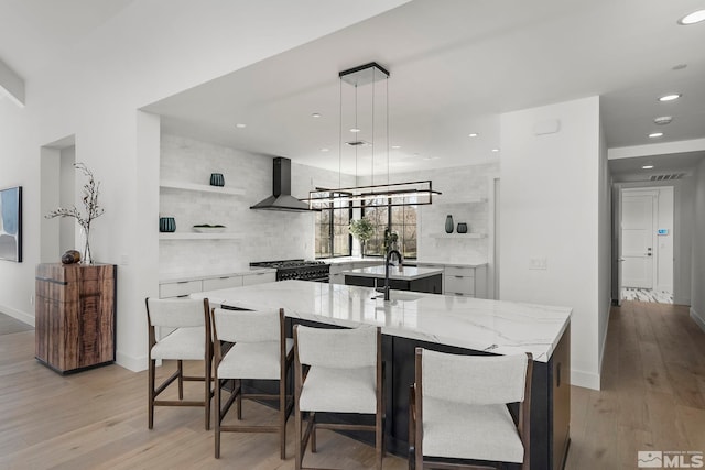 4060 Goodsell Ln, Reno, NV 89523 - kitchen featuring wall chimney exhaust hood, a kitchen island with sink, recessed lighting, open shelves, and light wood-type flooring