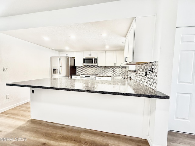449 Andria Dr, Stateline, NV 89448 - kitchen featuring appliances with stainless steel finishes, a peninsula, tasteful backsplash, light wood-type flooring, and white cabinets
