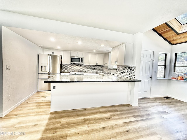449 Andria Dr, Stateline, NV 89448 - kitchen featuring appliances with stainless steel finishes, decorative backsplash, baseboards, a skylight, and vaulted ceiling