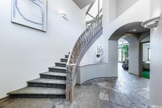 1185 Paddock Ln, Reno, NV 89521 - stairway featuring stone tile flooring, arched walkways, a towering ceiling, and baseboards