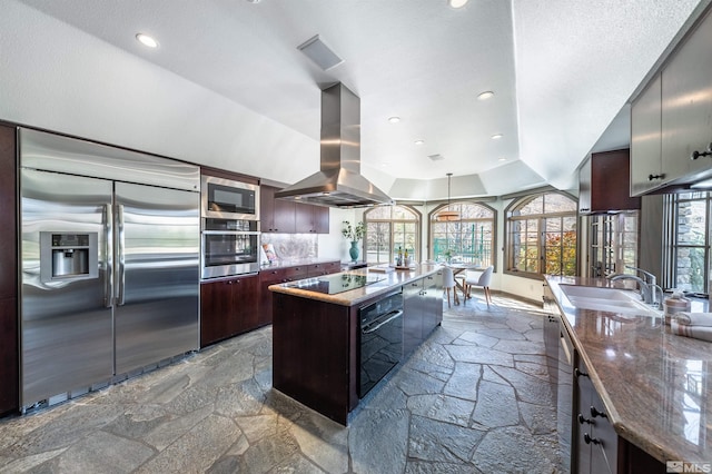 1185 Paddock Ln, Reno, NV 89521 - kitchen featuring built in appliances, a sink, stone tile floors, island range hood, and plenty of natural light