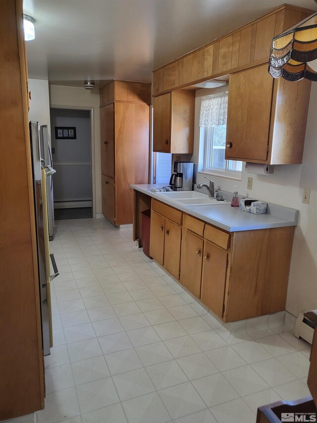 828 W Washington St, Carson City, NV 89703 - kitchen featuring a sink, light countertops, brown cabinets, and a baseboard heating unit