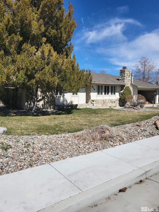 828 W Washington St, Carson City, NV 89703 - view of front of house featuring stucco siding, a chimney, a front lawn, and stone siding