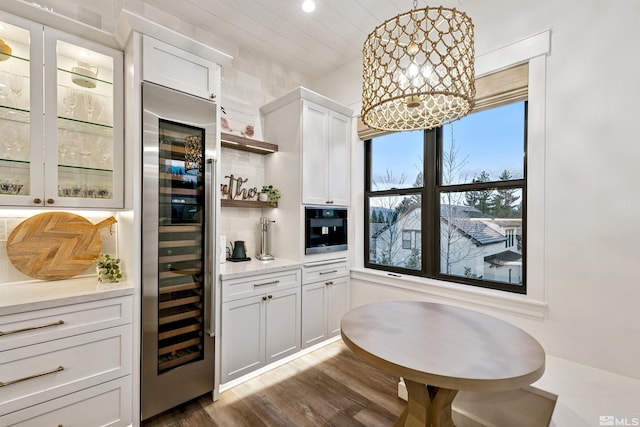 4312 Beaujolais St, Reno, NV 89511 - bar area with wine cooler, dark wood finished floors, black oven, a chandelier, and hanging light fixtures