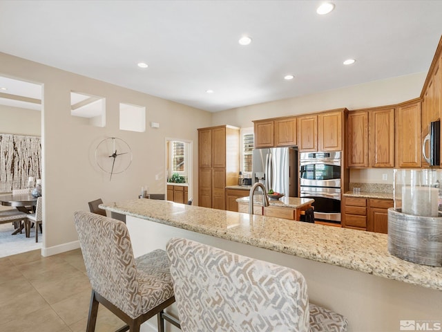 3502 Painted Vista Dr, Reno, NV 89511 - kitchen with appliances with stainless steel finishes, recessed lighting, light stone counters, a sink, and brown cabinetry