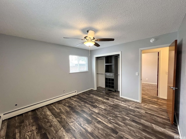 unfurnished bedroom with baseboard heating, dark wood-type flooring, a closet, a textured ceiling, and baseboards