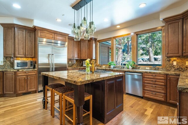 2147 The Back Rd, Glenbrook, NV 89413 - kitchen featuring appliances with stainless steel finishes, decorative backsplash, a breakfast bar, a kitchen island, and light wood finished floors