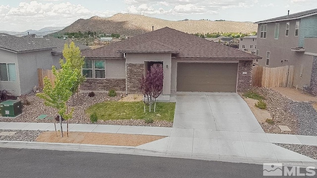 7216 Mustengo Dr, Reno, NV 89506 - view of front of home with an attached garage, concrete driveway, fence, roof with shingles, and stone siding