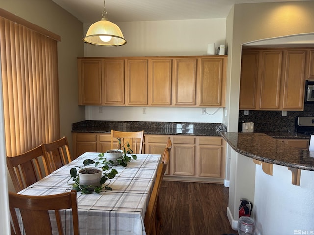 10316 Sterling View Ct, Reno, NV 89521 - kitchen with dark wood-type flooring, pendant lighting, decorative backsplash, a breakfast bar, and dark stone countertops