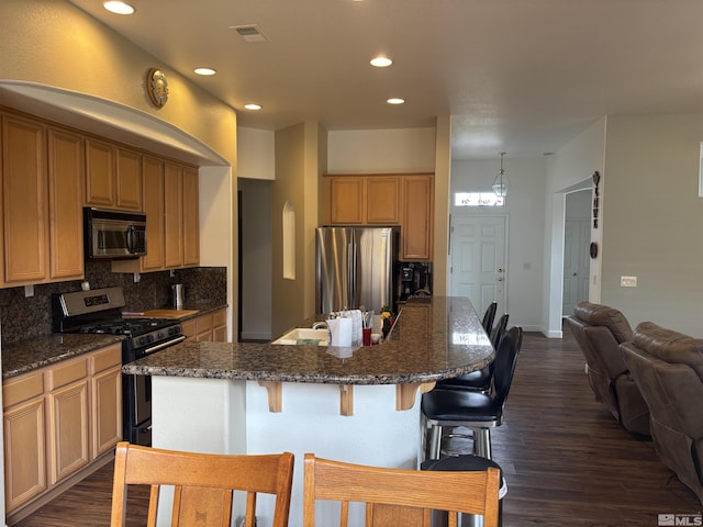 10316 Sterling View Ct, Reno, NV 89521 - kitchen with appliances with stainless steel finishes, tasteful backsplash, dark wood-type flooring, recessed lighting, and a kitchen breakfast bar