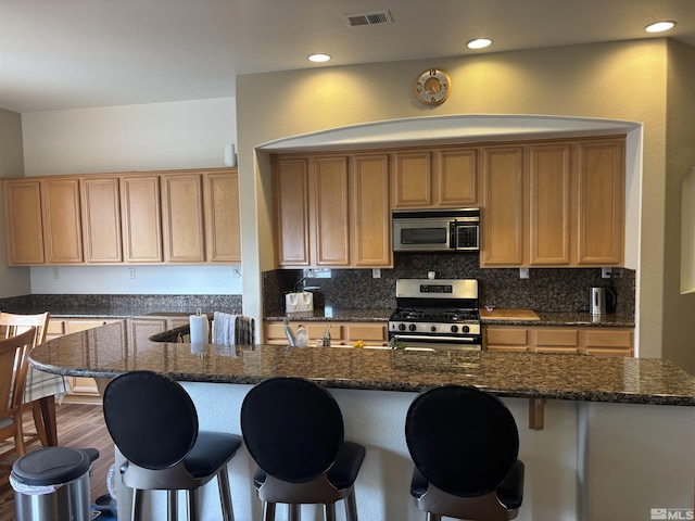 10316 Sterling View Ct, Reno, NV 89521 - kitchen featuring stainless steel appliances, a kitchen breakfast bar, dark stone countertops, decorative backsplash, and recessed lighting