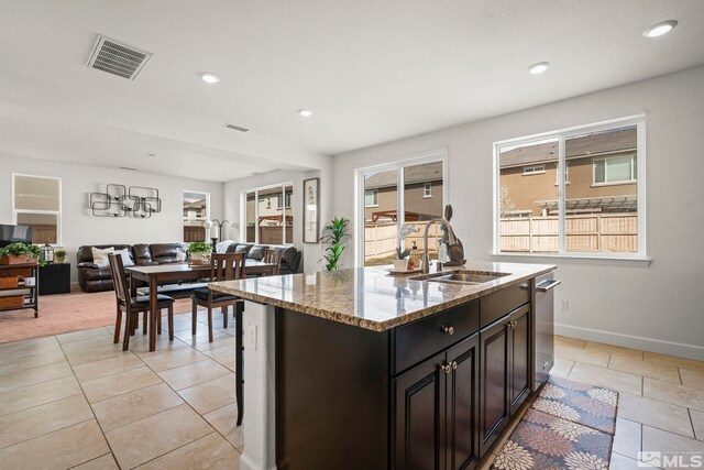 9726 Pachuca Dr, Reno, NV 89521 - kitchen with open floor plan, light stone counters, a kitchen island with sink, light tile patterned floors, and recessed lighting