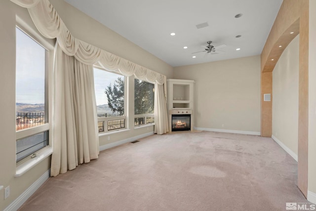 1150 Eagle Vista Ct, Reno, NV 89511 - unfurnished living room featuring light carpet, recessed lighting, a glass covered fireplace, baseboards, and a ceiling fan