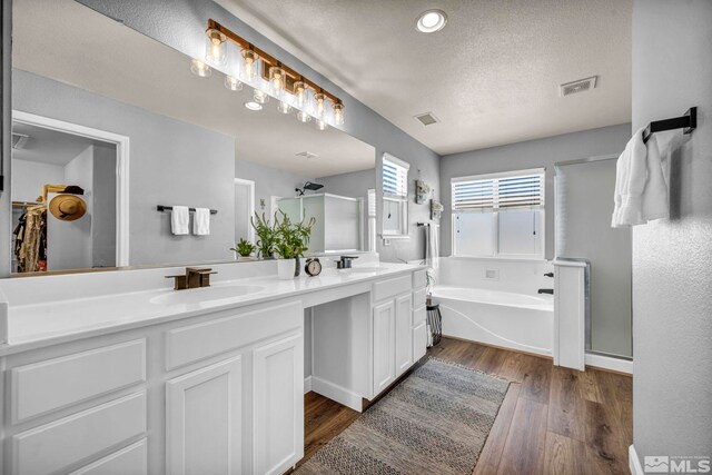 485 Sondrio Ct, Reno, NV 89521 - bathroom with a stall shower, a textured ceiling, double vanity, a garden tub, and wood finished floors