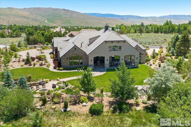 6645 De Chardin Ln, Reno, NV 89511 - view of front facade with stone siding, stucco siding, a tiled roof, a mountain view, and a chimney