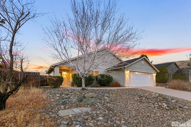 view of front facade featuring driveway, an attached garage, and fence