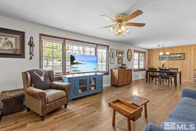 8700 Little Creek Rd, Reno, NV 89508 - living area featuring a ceiling fan, wooden walls, wood finished floors, a textured ceiling, and baseboards