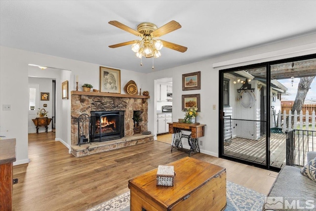 8700 Little Creek Rd, Reno, NV 89508 - living room featuring wood finished floors, ceiling fan, a stone fireplace, and baseboards