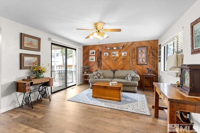 8700 Little Creek Rd, Reno, NV 89508 - living area featuring wooden walls, a ceiling fan, an accent wall, wood finished floors, and baseboards