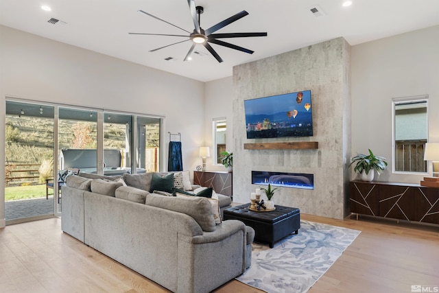 living area featuring a ceiling fan, wood finished floors, plenty of natural light, a large fireplace, and recessed lighting
