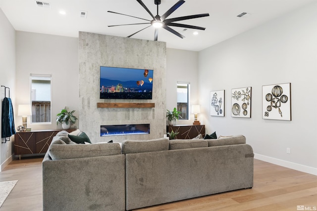 living room with light wood-style floors, a ceiling fan, baseboards, a large fireplace, and recessed lighting