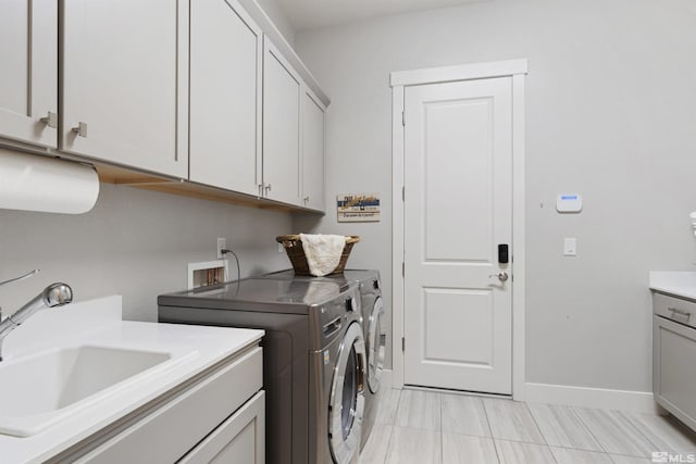 washroom with cabinet space, washing machine and clothes dryer, and baseboards