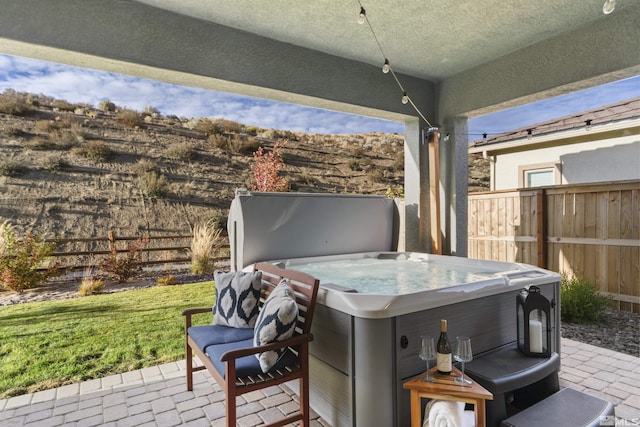 view of patio / terrace featuring a hot tub and fence