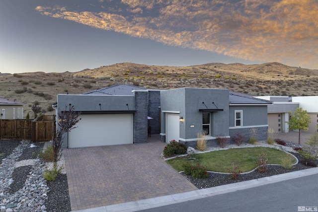 view of front of property with a mountain view, a garage, decorative driveway, stucco siding, and stone siding