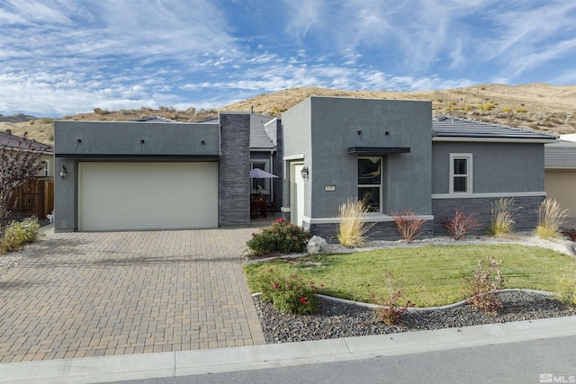 view of front of house featuring stucco siding, a mountain view, an attached garage, and stone siding
