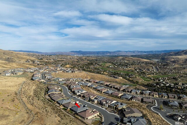 aerial view of property and surrounding area featuring nearby suburban area and a mountainous background