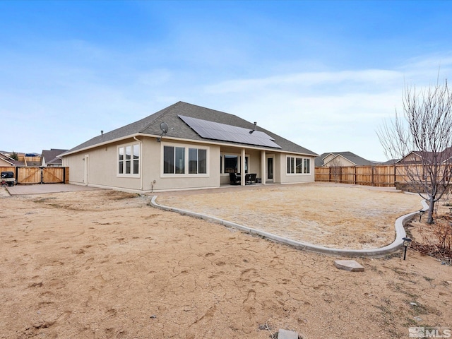 11641 Vista Park Dr, Sparks, NV 89441 - rear view of property featuring a fenced backyard, roof mounted solar panels, a patio area, and stucco siding
