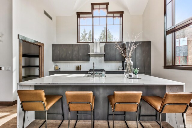 28 Beach Club Dr Unit 408, Stateline, NV 89449 - kitchen with wall chimney range hood, light stone countertops, a sink, a towering ceiling, and a kitchen bar