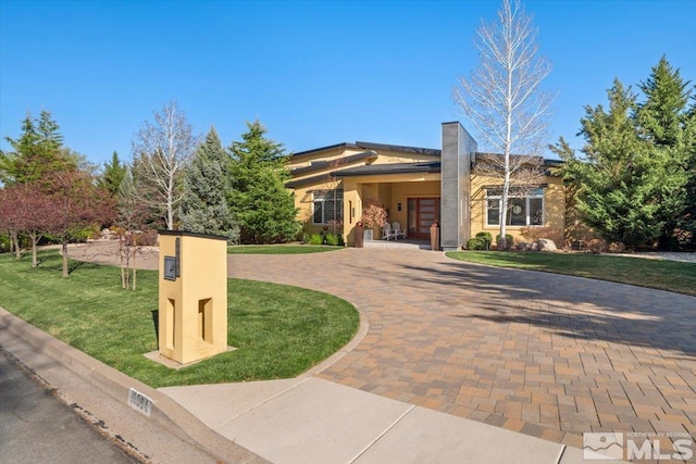 view of front of house featuring curved driveway, a front yard, and stucco siding