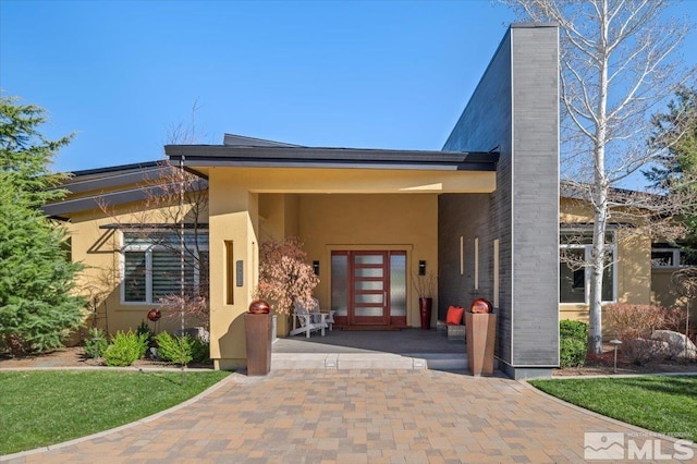 doorway to property featuring stucco siding and a chimney