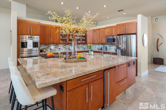 kitchen with stainless steel appliances, tasteful backsplash, a spacious island, recessed lighting, and brown cabinets