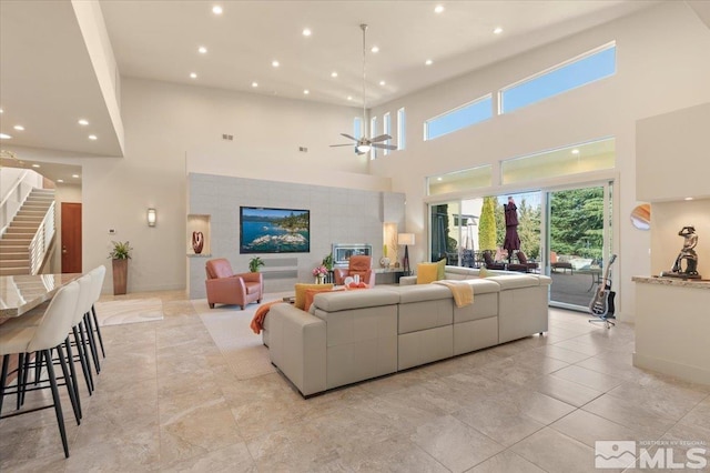 living area with a towering ceiling, recessed lighting, baseboards, stairs, and a ceiling fan