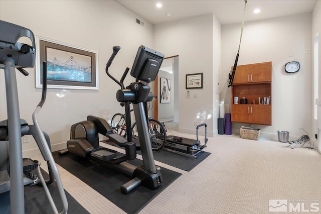 exercise room featuring recessed lighting, baseboards, carpet floors, and a towering ceiling