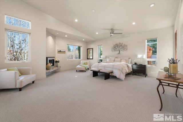 bedroom with carpet, recessed lighting, multiple windows, vaulted ceiling, and a fireplace