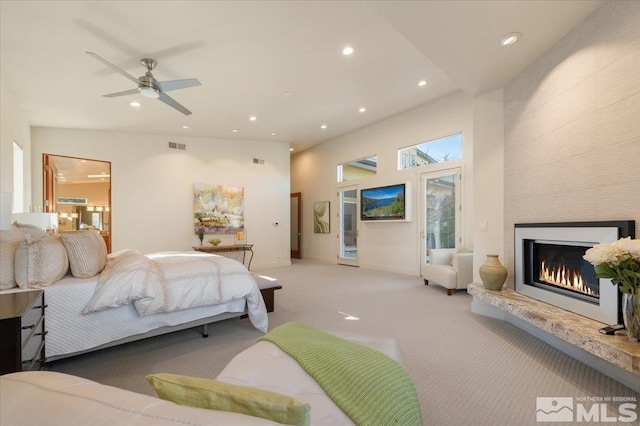 carpeted bedroom featuring recessed lighting, a tile fireplace, and a towering ceiling