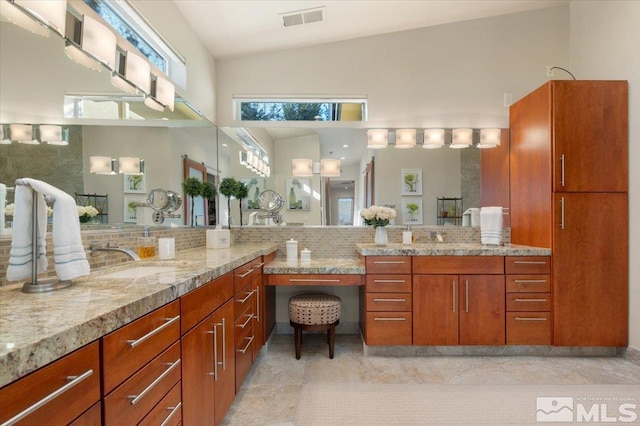 bathroom with backsplash, high vaulted ceiling, vanity, and a shower
