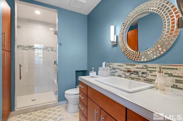 bathroom featuring a stall shower, toilet, vanity, tasteful backsplash, and tile patterned flooring