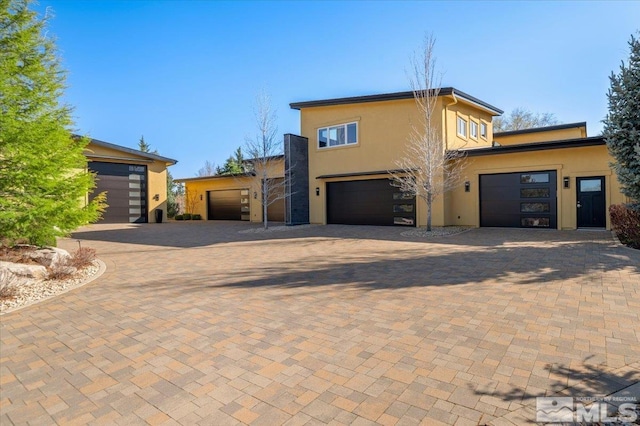 view of front of property featuring stucco siding, decorative driveway, and a garage