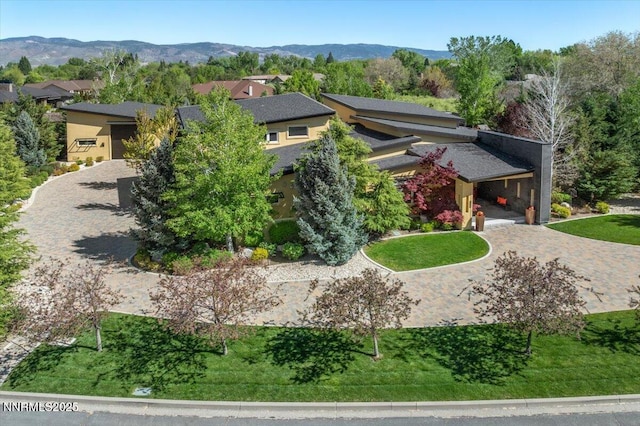 view of front facade with decorative driveway, a mountain view, stucco siding, and a residential view