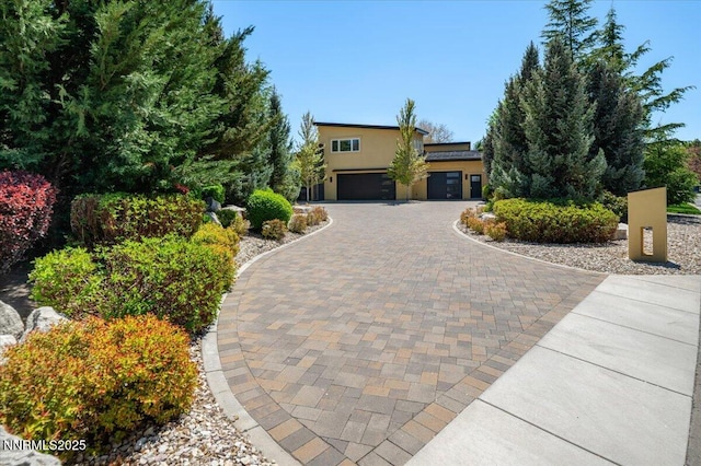 view of front of home with curved driveway, stucco siding, and an attached garage