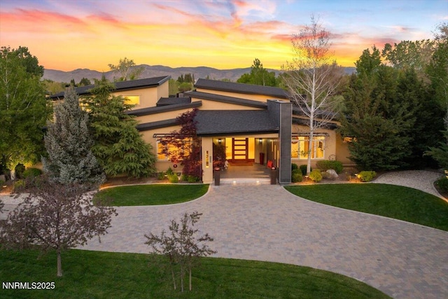 10064 Dixon Ln, Reno, NV 89511 - view of front of home featuring stucco siding, a front lawn, a mountain view, curved driveway, and covered porch